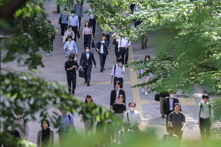 Office workers make their way from the Shinjuku Station on May 16 as they commute to work in central Tokyo. Japan's economy contracted 0.2 percent in the three months to March, registering the first quarterly drop in a year, according to cabinet office data released on May 16.