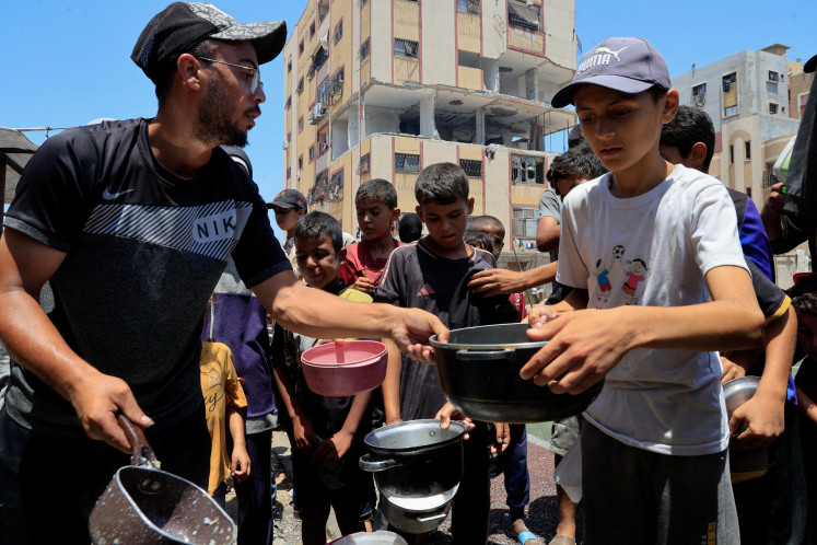 Palestinians gather to receive food from a charity kitchen, amid a hunger crisis, in Nuseirat, central Gaza Strip, July 29, 2025. 