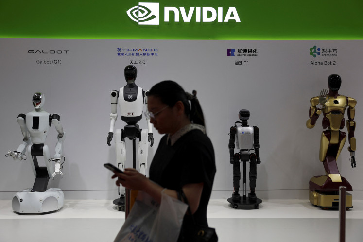 A woman walks past humanoid robots displayed at the Nvidia booth during the China International Supply Chain Expo in Beijing on July 16, 2025.
