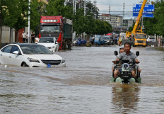 A man rides a motorcycle in a flooded street in Miyun district, northern Beijing on July 29, 2025. 