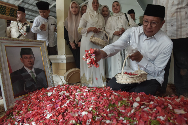 Former religious affairs minister and United Development Party (PPP) politician Lukman Hakim Saifuddin puts flowers on the grave of fellow former minister and PPP chair Suryadharma Ali at the Miftahul Ulum pesantren (Islamic boarding school) complex in West Cikarang, Bekasi regency, West Java on July 31, 2025. Suryadharma dies on Thursday early morning in South Jakarta, aged 68.