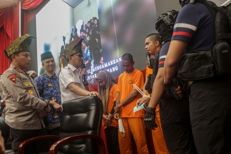 Migrant Workers Protection Minister Abdul Kadir Karding (third left), Riau Police chief Insp. Gen. Hery Heryawan (left) and acting Riau provincial administration secretary M. Job Kurniawan (second left) talk with an arrested human trafficking suspect at the Riau Police headquarters in Pekanbaru on July 17, 2025. The Riau Police arrested 11 suspects for allegedly illegally sending migrant workers to Malaysia and released 100 prospective unauthorized workers to be sent to the neighboring country.