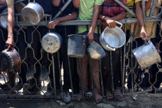 Palestinians carry empty pots as they wait to receive lentil soup at a food distribution point in Gaza City on Aug. 2, 2025. The World Health Organisation (WHO) warned on July 27 that malnutrition was reaching “alarming levels“ in Gaza.