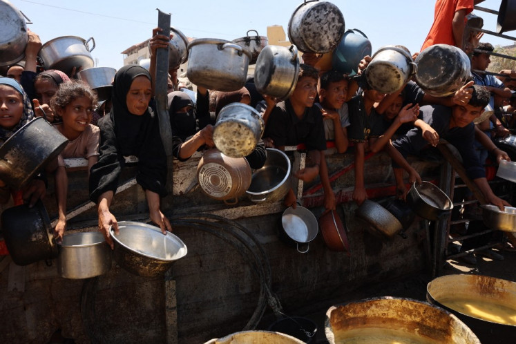 Far from enough: Palestinians receive lentil soup on Saturday at a food distribution point in Gaza City.
