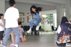 Children play a game that involves jumping over a rope on June 19, 2025, during an event organized by Traditional Games Returns (TGR), a community that promotes and preserves Indonesian folk games.