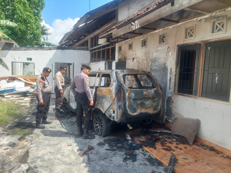 Police officers observe a charred Toyota Avanza on Aug. 3, 2025, in Denpasar, Bali. An Australian, identified as WRJ, stole the car from a club in Kuta, Badung regency, Bali, in the early hours of Sunday. 
