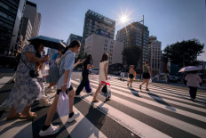 People cross a street on a hot day in Tokyo on August 4, 2025. 
