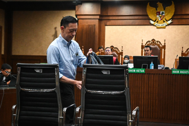 Former trade minister Thomas Lembong walks to the defendant's chair on July 9 during a hearing against him at the Jakarta Corruption Court in Jakarta. Prosecutors requested that Thomas face seven years behind bars for his alleged role in a corruption case pertaining to the import of raw sugar.