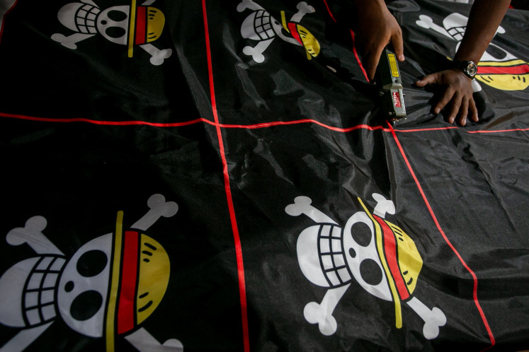 A worker cuts the “Jolly Roger“ flag from Japanese anime “One Piece“ during the printing process on Aug. 5 in Karanganyar regency, Central Java. Printing business owners in the regency say that the demand for the pirate flag from the anime has increased threefold in early August.