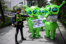 A security guard stops a group of activists from the People for the Ethical Treatment of Animals (PETA) wearing alien costumes on July 31, 2025, during an environmental rally in Manila’s Makati Central Business District.