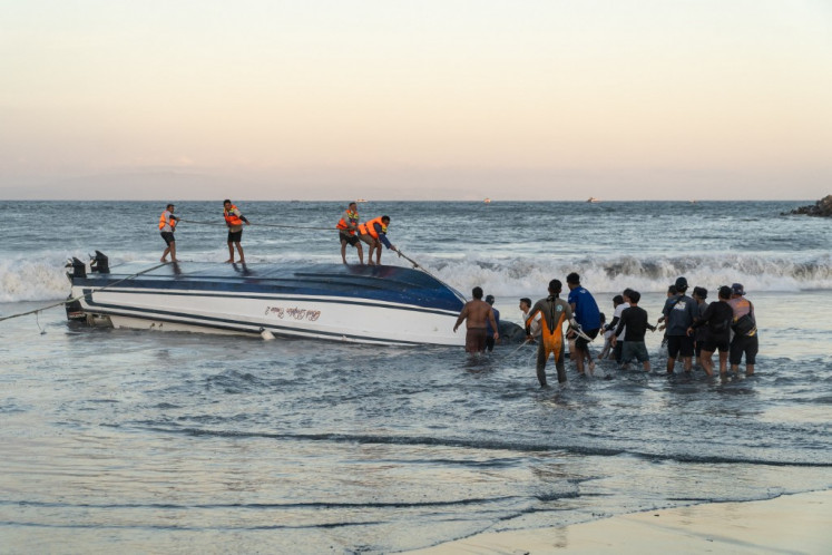 Locals and rescue workers attempt to recover an overturned speedboat after it sank near Sanur port in Bali on August 5, 2025. 