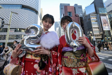 Two young women wearing kimonos to mark “Coming-of-Age Day“ when the country honors people who turn 20 this year to signify adulthood, pose for a photo and hold balloons for “20“ to celebrate in the Ginza area of central Tokyo on January 13, 2025.