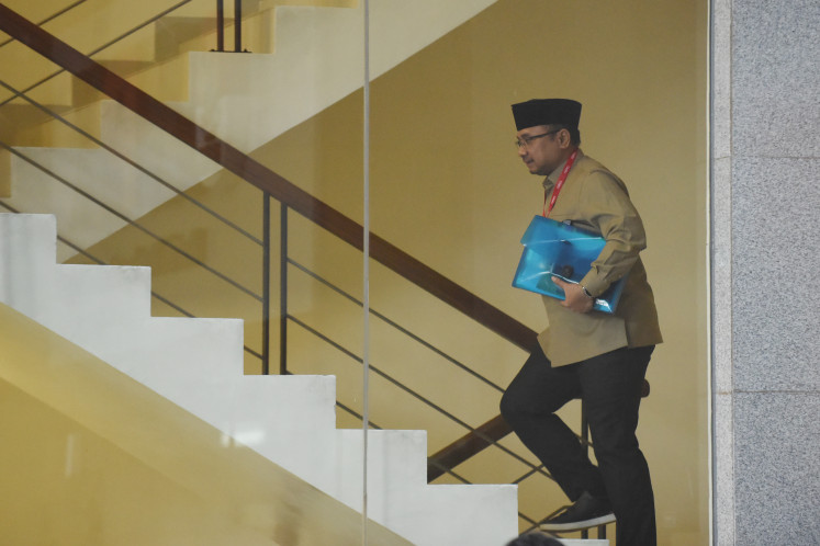 Former religious affairs minister Yaqut Cholil Qoumas climbs the stairs in the South Jakarta headquarters of Corruption Eradication Commission (KPK) to attend his questioning on Aug. 7, 2025.
