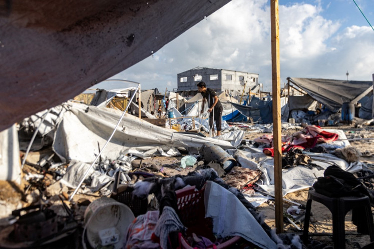 A man walks with crutches on Tuesday as he inspects the scene in the aftermath of overnight Israeli bombardment on a camp sheltering displaced people in the Mawasi area of Khan Yunis in the southern Gaza Strip. According to figures from Gaza's health ministry, more than 60,933 Palestinians have been killed in the Palestinian territory after the Israeli army devastated large parts of it in 22 months of combat sparked by the Oct. 7, 2023, cross-border attacks by Hamas that killed 1,219 people and saw hundreds kidnapped.