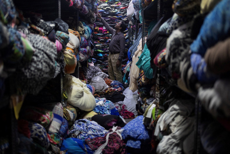 A worker looks for a fabric for dresses inside a store at a garment manufacturing unit in Noida, India, on Aug. 7, 2025.