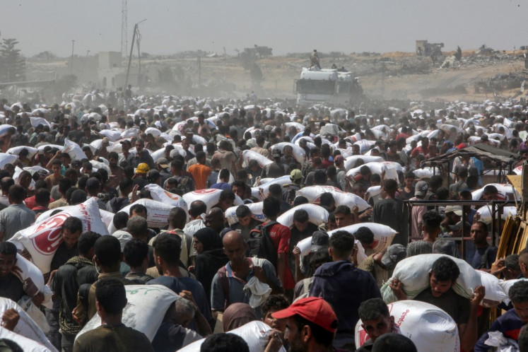 Displaced Palestinians carry food parcels as they raid trucks carrying humanitarian aid in Khan Yunis, in the southern Gaza Strip on August 9, 2025. 