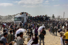 Displaced Palestinians carry food parcels from trucks carrying humanitarian aid on Aug. 9 in Khan Yunis, the southern Gaza Strip. Nearly two years into the war in Gaza, Israel's Prime Minister Benjamin Netanyahu faces mounting pressure to secure a truce to pull the territory's more than 2 million people back from the brink of famine and free the hostages held by Palestinian militants.