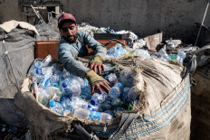 An Afghan worker loads plastic bottles into a sack at a recycling yard in Kabul on August 5, 2025.