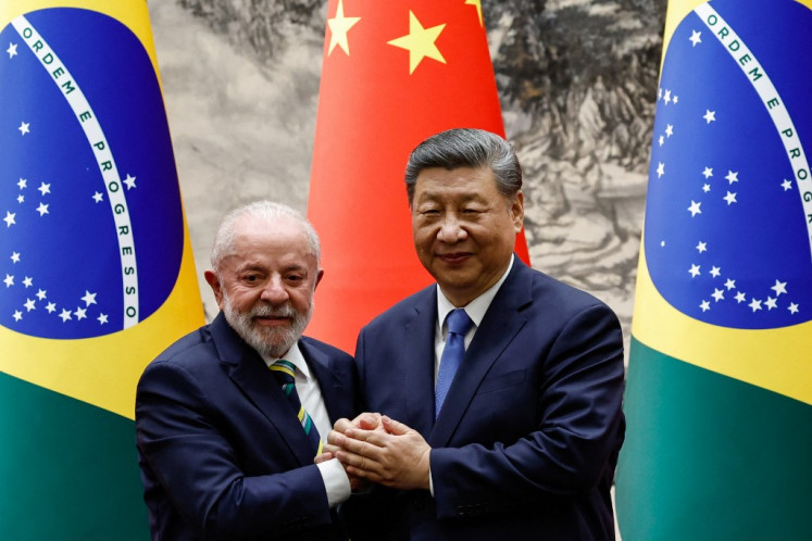 Chinese President Xi Jinping (R) shakes hands with Brazil's President Luiz Inacio Lula da Silva after a signing ceremony and a joint press conference, at the Great Hall of the People in Beijing on May 13, 2025. 