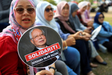A supporter of former Malaysian Prime Minister Najib Razak holds a hand fan with a picture of Najib printed on it, outside the Malaysian federal court, where his case is being heard, at Putrajaya, Malaysia on August 13, 2025. 