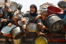 Palestinians gather to receive cooked meals from a food distribution center in Gaza City on Aug. 13, 2025.