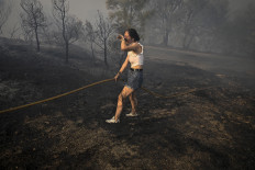 A woman tries to extinguish a wildfire near the village of Larouco, in the province of Ourense, in northwestern Spain, on August 13, 2025. Firefighters in Spain continue to battle fires across the country, where one volunteer has died while trying to extinguish a blaze, according to local authorities. Another man has died of burns near the capital city, Madrid. Across Europe, thousands have been forced from their homes by wildfires fueled by an enduring heatwave.
