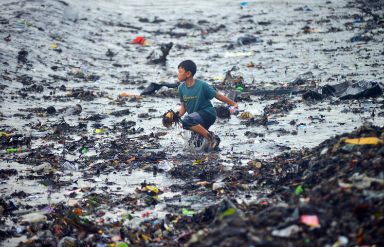 A child collects reusable waste at Muaro Lasak Beach, Padang, West Sumatra, on Aug. 8, 2025. Marine debris and various types of waste carried from the river have piled up on the beach following heavy rain.