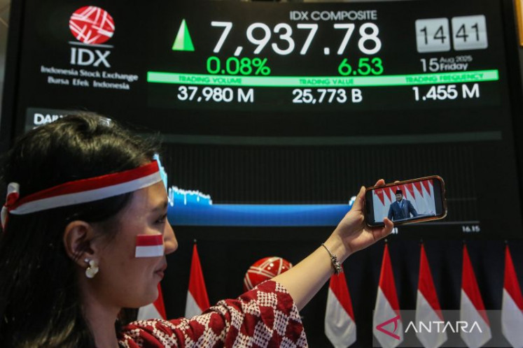 A worker watches President Prabowo Subianto’s State of the Nation address on Friday on a smartphone at the Indonesia Stock Exchange (IDX) in Jakarta. The IDX Composite index briefly reached an all-time high above 8,000 points during intraday trading as the President delivered his speech.