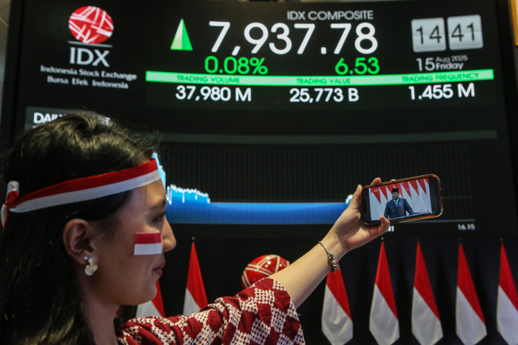 A worker watches President Prabowo Subianto’s State of the Nation address on Friday on a smartphone at the Indonesia Stock Exchange (IDX) in Jakarta. The IDX Composite index briefly reached an all-time high above 8,000 points during intraday trading as the President delivered his speech.