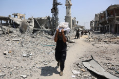 A Palestinian man walks past destroyed buildings carrying salvaged items in the al-Tuffah neighbourhood of Gaza City on Aug. 14, 2025, following more than 22 months of war between Israel and the Palestinian militant group Hamas. The Israeli military said on August 13, that it had approved the framework for a new offensive in the Gaza Strip, as Hamas condemned what it called “aggressive“ Israeli ground incursions in Gaza City.