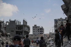 Palestinians look at aid packages that are airdropped over Gaza, in Gaza City on August 8, 2025.