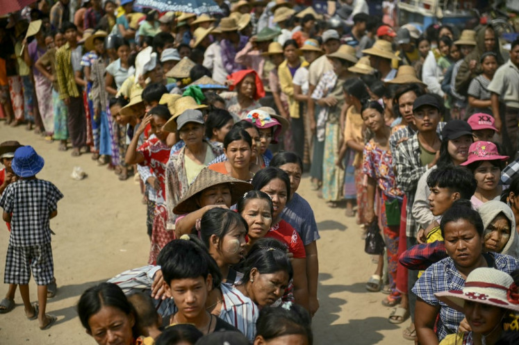 People wait to receive food at an aid distribution point in Sagaing on April 3, 2025, following the 7.7-magnitude shallow earthquake that struck central Myanmar on March 28, killing nearly 3,000 people and leaving thousands without homes.
