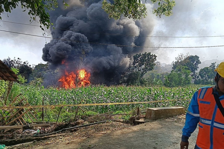 A firefighter observes the oil well fire in Gandu village, Bogorejo district, Blora regency, Central Java, on Aug. 17, 2025, which killed three people and forced 50 families to evacuate. 
