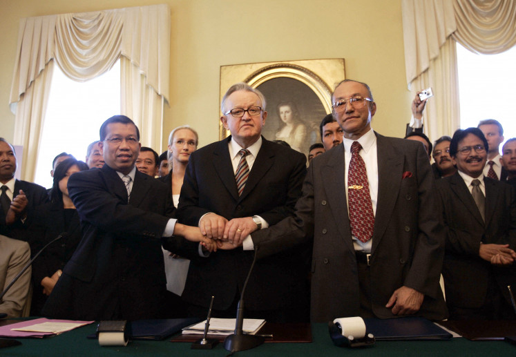 Then-law and human rights minister Hamid Awaludin (left) and the chairman of the Free Aceh Movement (GAM) negotiating delegation Malik Mahmud (right) and chairman of the board of the Crisis Management Initiative Finland's Martti Ahtisaari (center) shake hands after signing the peace agreement on Aug. 15, 2005 in Helsinki. The pact aimed at ending nearly three decades of violent conflict in Aceh between GAM and government forces, which claimed almost 15,000 lives. Two previous truces had failed.