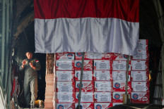 Aircrew stand next to an Indonesian flag and aid packages inside a C-130 Hercules military cargo plane at Halim Perdanakusuma Air Force Base in Jakarta on Aug. 13, 2025, before deployment to deliver aid to Palestinians in war-torn Gaza.