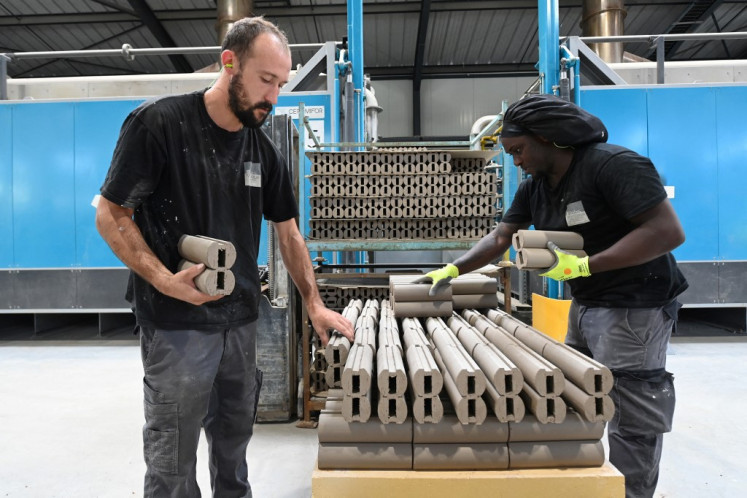 Workers load a kiln with terracotta tiles and facing bricks for facades, before firing them in an electric kiln in the Rairies Montrieux factory, in les Rairies, near Angers, on July 17, 2025.