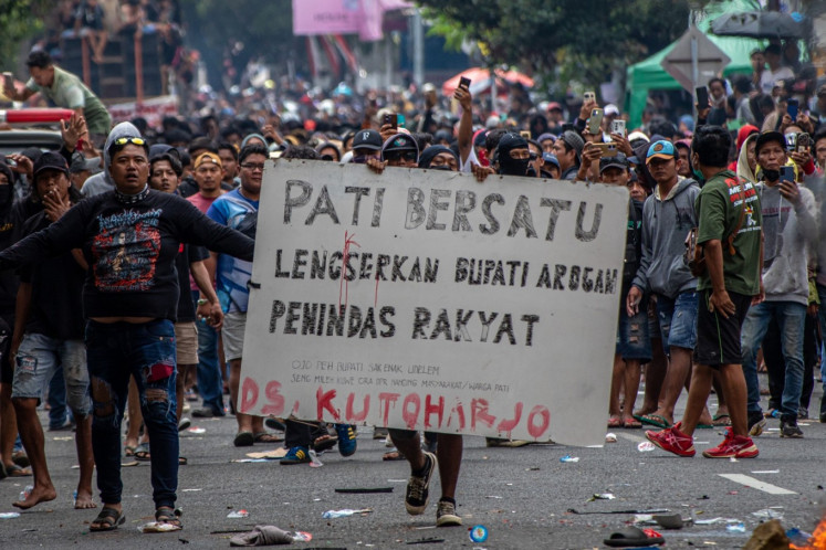 A protester holds a sign that reads “Pati united. Down with arrogant regent who oppresses the people“ during a protest in Pati, Central Java on Aug. 13, 2025. (Antara/Aji Styawan)