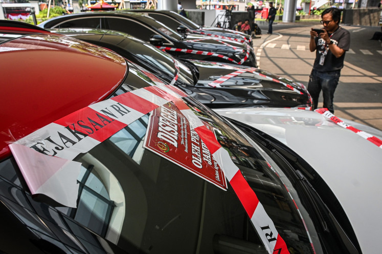 A man takes photos of luxury cars seized by the Attorney General's Office (AGO) in relation to the corruption case implicating oil tycoon Riza Chalid at the AGO office in Jakarta on Aug. 5, 2025. 