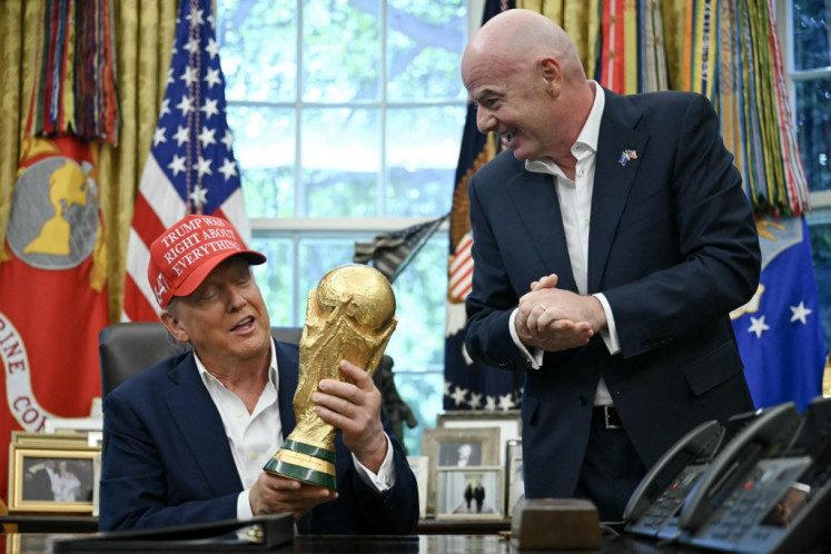 United States President Donald Trump joined by FIFA president Gianni Infantino (right) holds the World Cup Trophy as he makes an announcement in the Oval Office of the White House in Washington, DC, on Aug. 22, 2025. Trump announced the 2026 World Cup draw will be held on Dec. 5 at Washington's Kennedy Center.