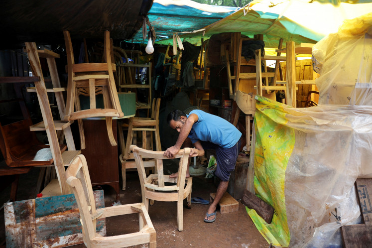 A man works on a chair at a shop in a furniture market in New Delhi on July 31, 2025.