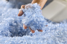 A worker shows shredded plastic bottles to be recycled on Aug. 22 at the Bali PET Recycling facility in Denpasar, Bali.
