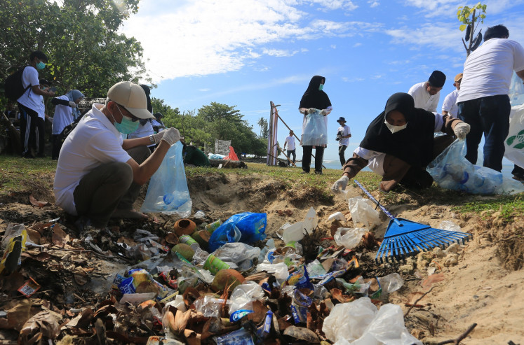 Volunteers and local residents clean up plastic waste on Aug. 23 at a beach in Lhok Bubon village in West Aceh regency, Aceh.