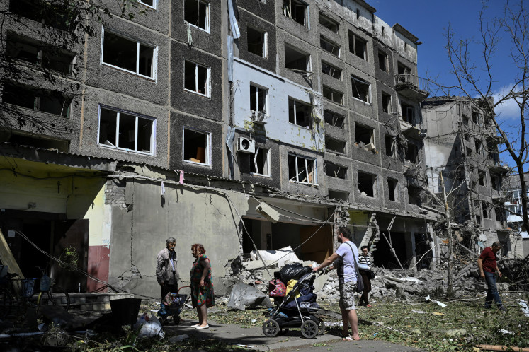 Local residents carry their belongings out of a heavily damaged residential building following a Russian strike in the town of Bilozerske, Donetsk region on August 12, 2025, amid the Russian invasion of Ukraine. The fate of several regions of the country occupied by Russian troops is at the center of diplomatic maneuvering to find a solution to Russia's invasion of Ukraine. 
