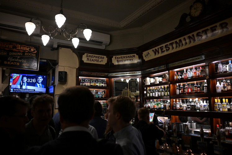 A TV broadcasts election updates as people gather inside the Westminster Arms pub in London on July 4, 2024 as polls close in Britain's general election. 