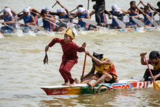 A boy dances on the bow of a traditional longboat during the Pacu Jalur longboat race festival on the Kuantan River in Kuantan Singingi Regency, Riau Province, on August 21, 2025. 