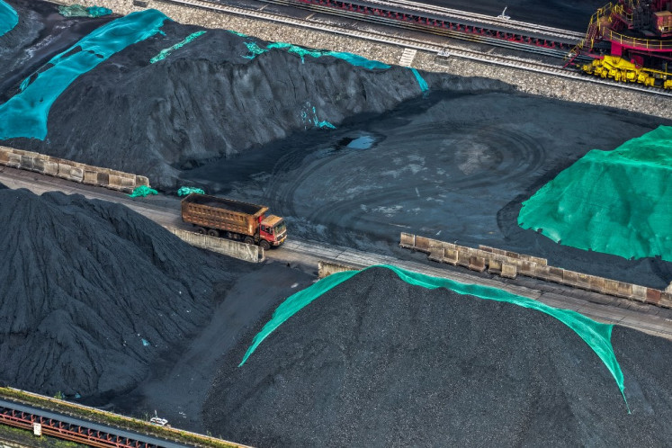 A truck drives between piles of coal at a coal yard beside the Yangtze River in Nanjing, in China's eastern Jiangsu province on July 22, 2025.