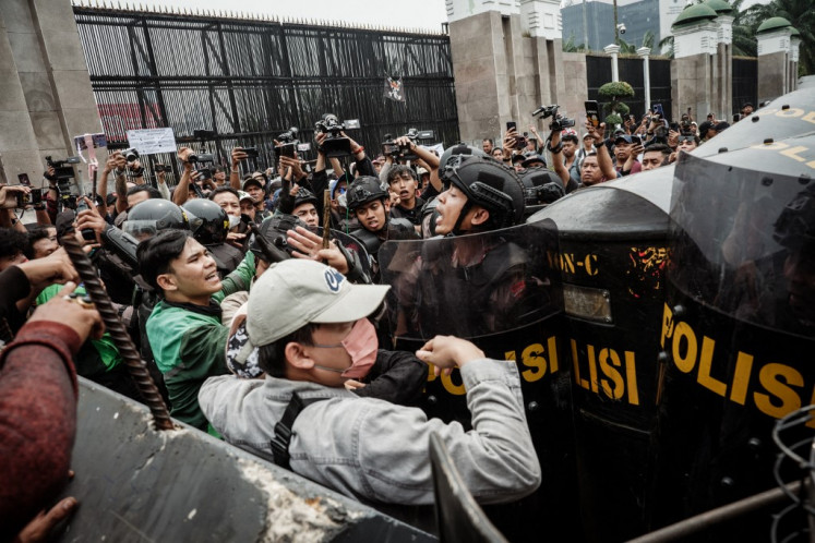 Protesters are blocked by police with shields during a demonstration demanding the dissolution of the House of Representatives on a street in front of the House building in Jakarta on August 25, 2025. 