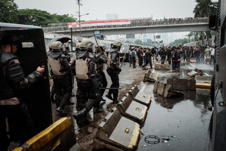 Police move forward as they dodge rocks thrown by protesters during a demonstration demanding the dissolution of the House of Representatives on a street in front of the House complex in Jakarta on Aug. 25, 2025.
