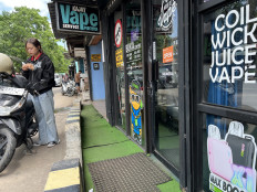 A women checks her vaping pod after buying the e-liquid at Vape Kajay store in Jodoh, Batam city, Riau Islands, on Aug. 26, 2025. Batam is set to benefit after neighboring Singapore declared on Aug. 17, 2025, restrictions and bans on vaping. 