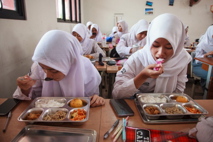 Students eat lunch on the first day of a free-meal program at 11 State Senior High School in East Jakarta on January 6, 2025. 


